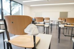 In einem Klassenzimmer hängt eine FFP2-Maske an einer Stuhllehne
